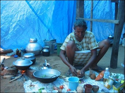 Vincent Daisy (44), wife of a fisherman and mother of two, cooks lunch in a welfare camp in Thampattai in the afternoon. She says she received only rice, sugar and flour from relief workers and have to buy vegetables, chillie powder, onion, green chillies, coconut and other spices at the shop. She earns Rs 300 clearing rubble. She says she is sick after working for long hours in the heat and finds difficult to make ends meet after her husband lost his job in Tsunami.  The tent they are living in is very hot that no one can stay inside more than a few minutes. Some camp residents are using coconut fronds as roof to make the tents cooler.