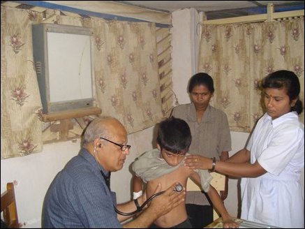 Dr Karunyan Arulanandam, a Paediatrician from Calfornia USA, examining a child while a local nurse helps out.