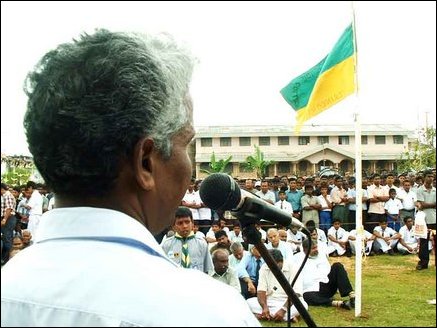 Sri Koneswara Hindu College Principal M.Rajaratnam presiding over the condolence meeting, College flag is seen half-mast with the college in background